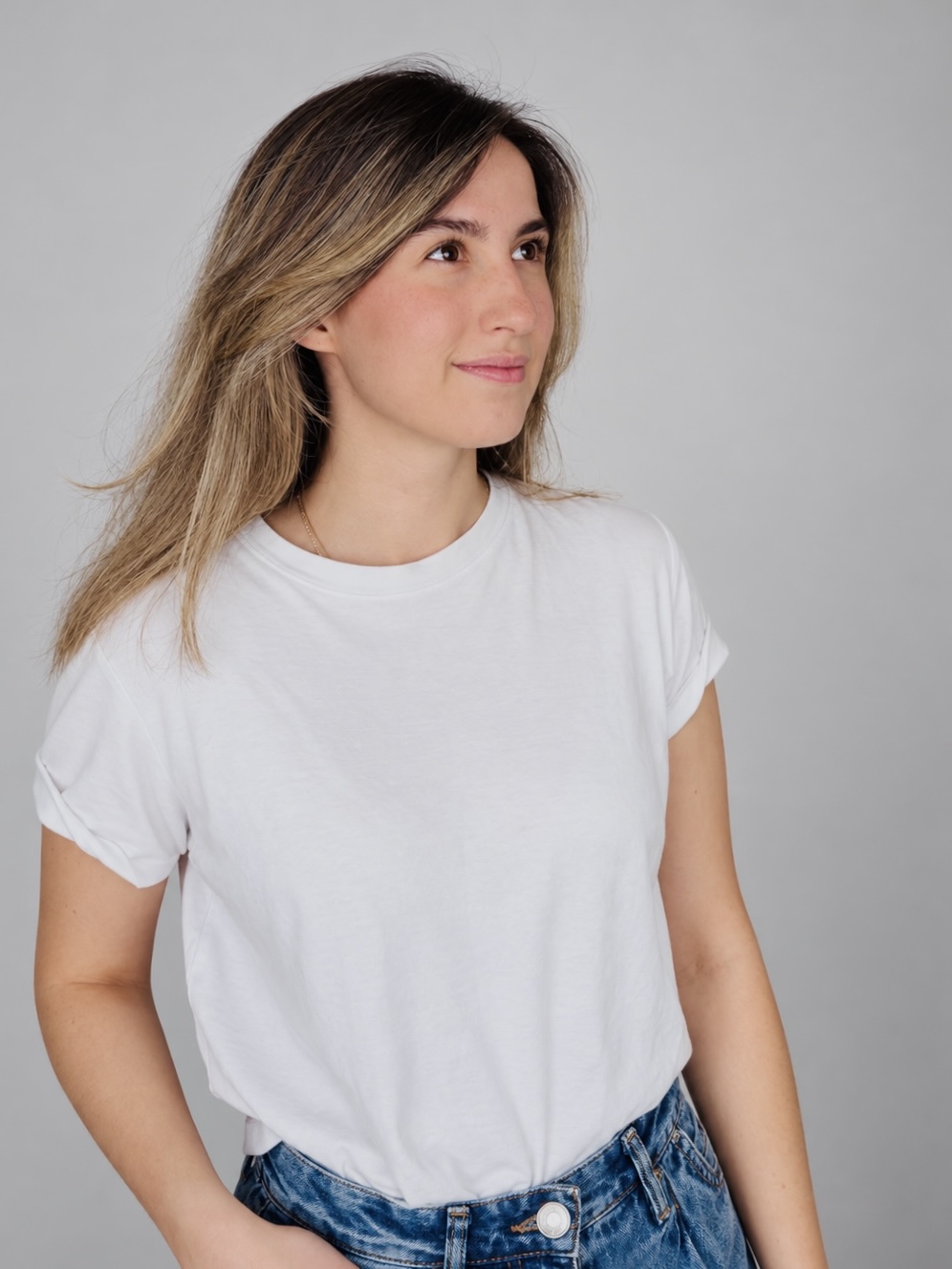 Ju in a white T-shirt against a soft grey background, looking to the right